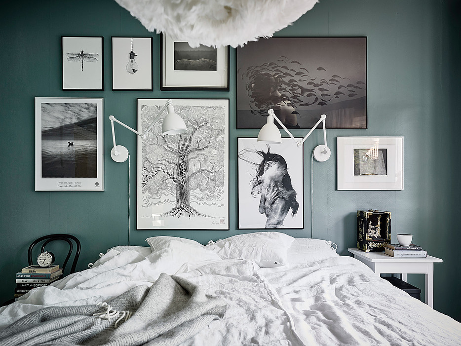 large picture wall on a painted dark green bedroom wall