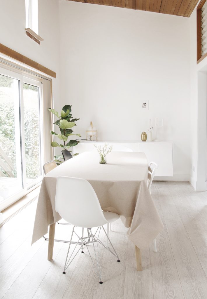 white dining room with high ceiling and green plants 