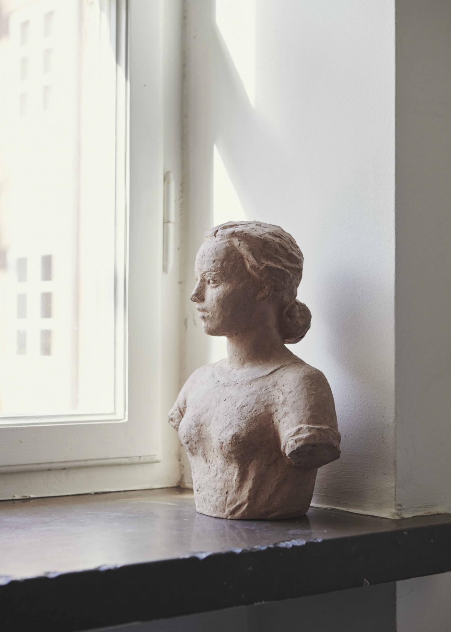 Female bust on a window sill in a minimal white apartment